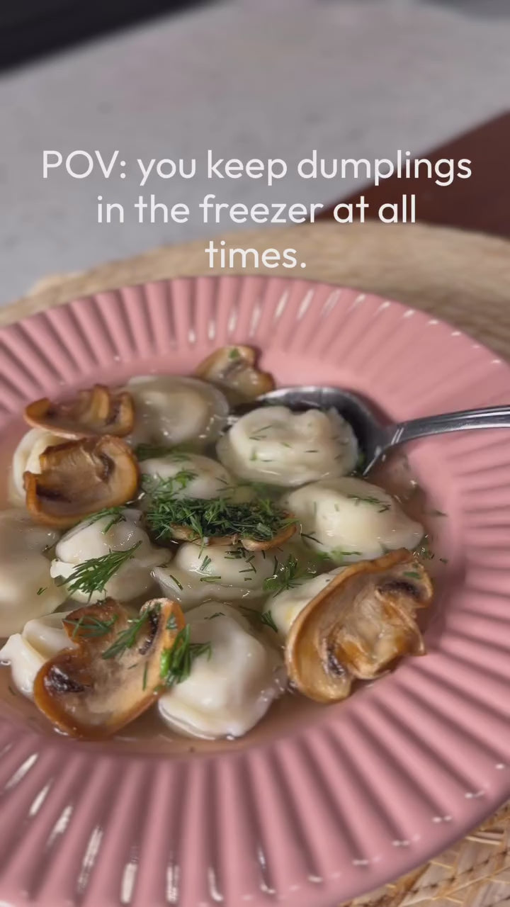 Close-up bite of a Luda's pelmeni dumpling with sour cream and green onions