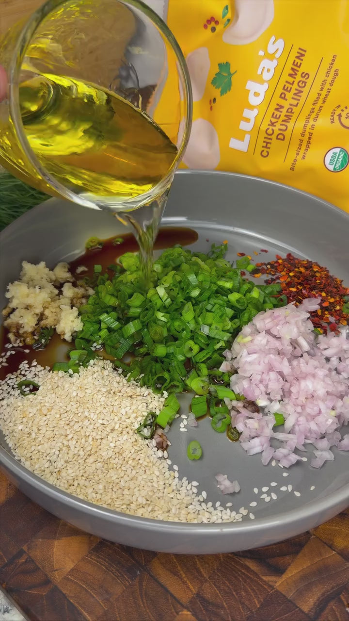 Crispy chili oil pelmeni: Luda's chicken pelmeni pan-seared until golden, tossed in sizzling garlic and chili oil with sesame and green onions