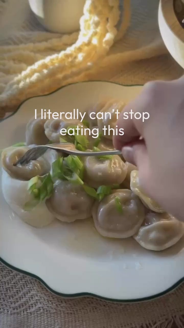 A plate of Luda's organic pork pelmeni dumplings with a fork, meat filling visible