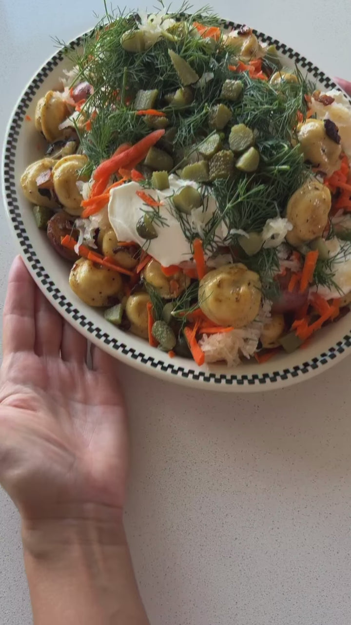 Slavic salad with pan-fried Luda's pork pelmeni, crispy potatoes with bacon, fried cabbage, carrots, sauerkraut, pickles, dill and sour cream